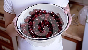 Child Holding Full Bowl Red Cherries in Hands While Standing in Kitchen. 4K