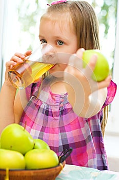 Child holding green apple and drinking juice