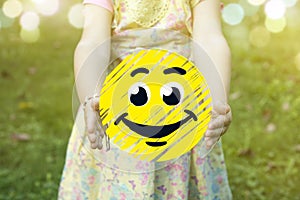 Child holding a happy smiley icon as success concept outdoors on a sunny day