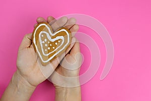 Child holding a heart cake on a pink background, the concept of Valentine& x27;s day or Christmas