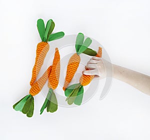 The child is holding a knitted carrot in his hand. Easter rabbit. Child`s hand.