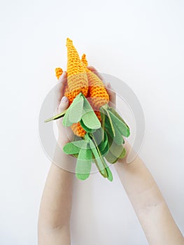 The child is holding a knitted carrot in his hand. Easter rabbit. Child`s hand.