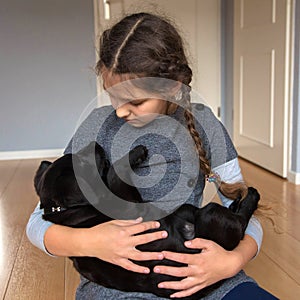 The child is holding a Labrador puppy