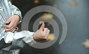 Child holding a little snail in hand outdoors