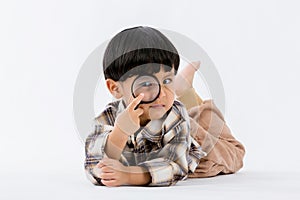 Child holding magnifying glass on white background. Boy with a magnifying glass in studio.