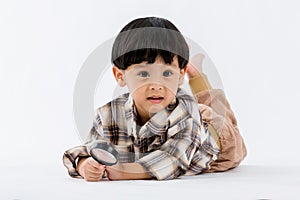 Child holding magnifying glass on white background. Boy with a magnifying glass in studio.