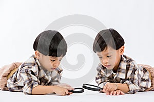 Child holding magnifying glass on white background. Boy with a magnifying glass in studio.