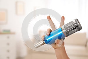 Child holding microphone at home, closeup