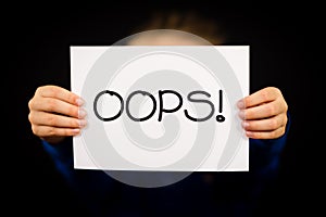 Child holding OOPS sign