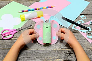 Child holding paper butterfly crafts in hands. Child shows a fun paper crafts. Stationery on an old wooden table