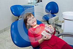 A child is holding a plastic jaw mock, at the dentistÃ¢â¬â¢s photo