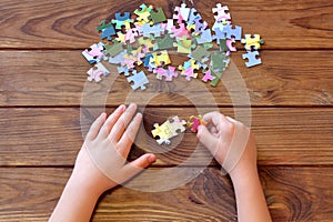 Child holding puzzles in hands. A set of jigsaw puzzles on wooden table