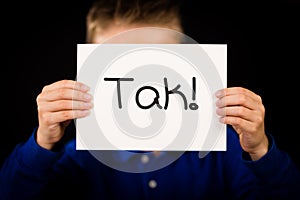 Child holding sign with Danish word Tak - Thank You