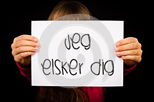 Child holding sign with Danish words Jeg Elsker Dig - I Love You