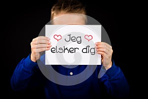 Child holding sign with Danish words Jeg Elsker Dig - I Love You