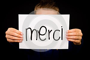 Child holding sign with French word Merci - Thank You photo