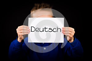 Child holding sign with German word Deutsch - German in English