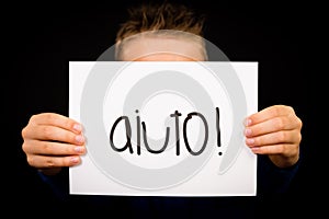 Child holding sign with Italian word Aiuto - Help photo