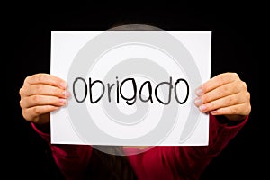 Child holding sign with Portuguese word Obrigado - Thank You