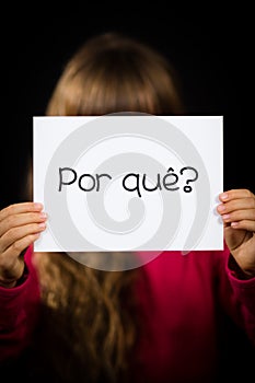 Child holding sign with Portuguese word Por Que - Why