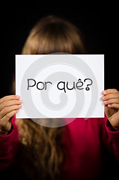 Child holding sign with Portuguese word Por Que - Why photo