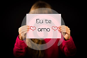 Child holding sign with Portuguese words Eu Te Amo - I Love You