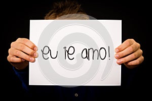Child holding sign with Portuguese words Eu Te Amo - I Love You photo