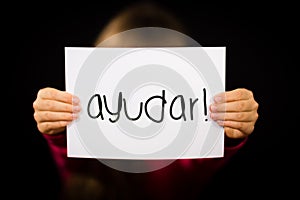 Child holding sign with Spanish word Ayudar - Help photo