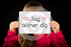 Child holding sign with Swedish words Jag Alsker Dig - I Love Yo