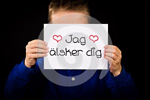 Child holding sign with Swedish words Jag Alsker Dig - I Love Yo