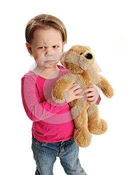 Child holding a teddy bear with mad expression