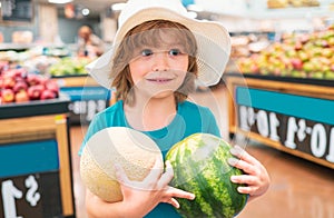 Child holding watermelon in supermarket. Sale, consumerism and kids concept. Vegetables in store.