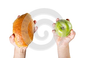 The child holds an apple and a bun to choose from