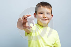 Child holds big white toy tooth on a blue background. Caring for teeth. Dentistry and healthcare concept. Healthy teeth concept
