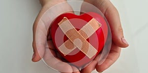 Child holds broken heart sealed with band-aid