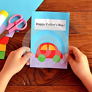 Child holds a card in his hands. Greeting card Happy father's day. Paper sheets, scissors, glue