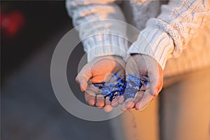 The child holds christmas blue sparkles in his hands.