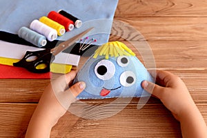 Child holds a felt monster in his hands. Felt Halloween ornament