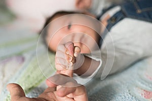 Child holds finger. Baby hand gently holding adult`s finger