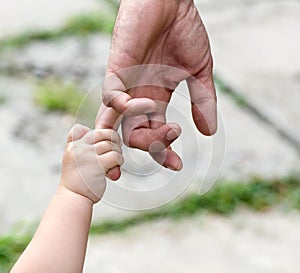 Child holds the finger of a hand of the father