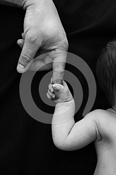 child holds his father& x27;s finger, black and white