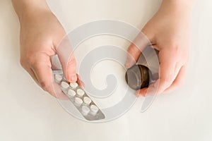 Child holds in one hand a package of pills and chocolate candy in the second hand