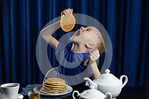A child holds a pancake and eating