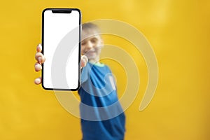 child holds the phone in his hand for advertising on a yellow background. Color