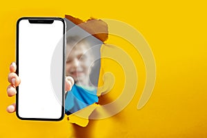 child holds the phone in his hand for advertising on a yellow background. Color