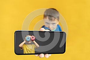 child holds the phone in his hand for advertising on a yellow background. Color