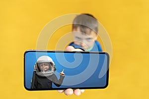 Child holds the phone in his hand for advertising on a yellow background. Color