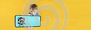 child holds the phone in his hand for advertising on a yellow background. Color