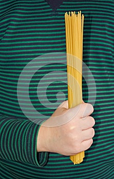 A child holds spaghetti in his hand