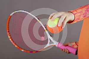 The child holds a tennis racket and a tennis ball